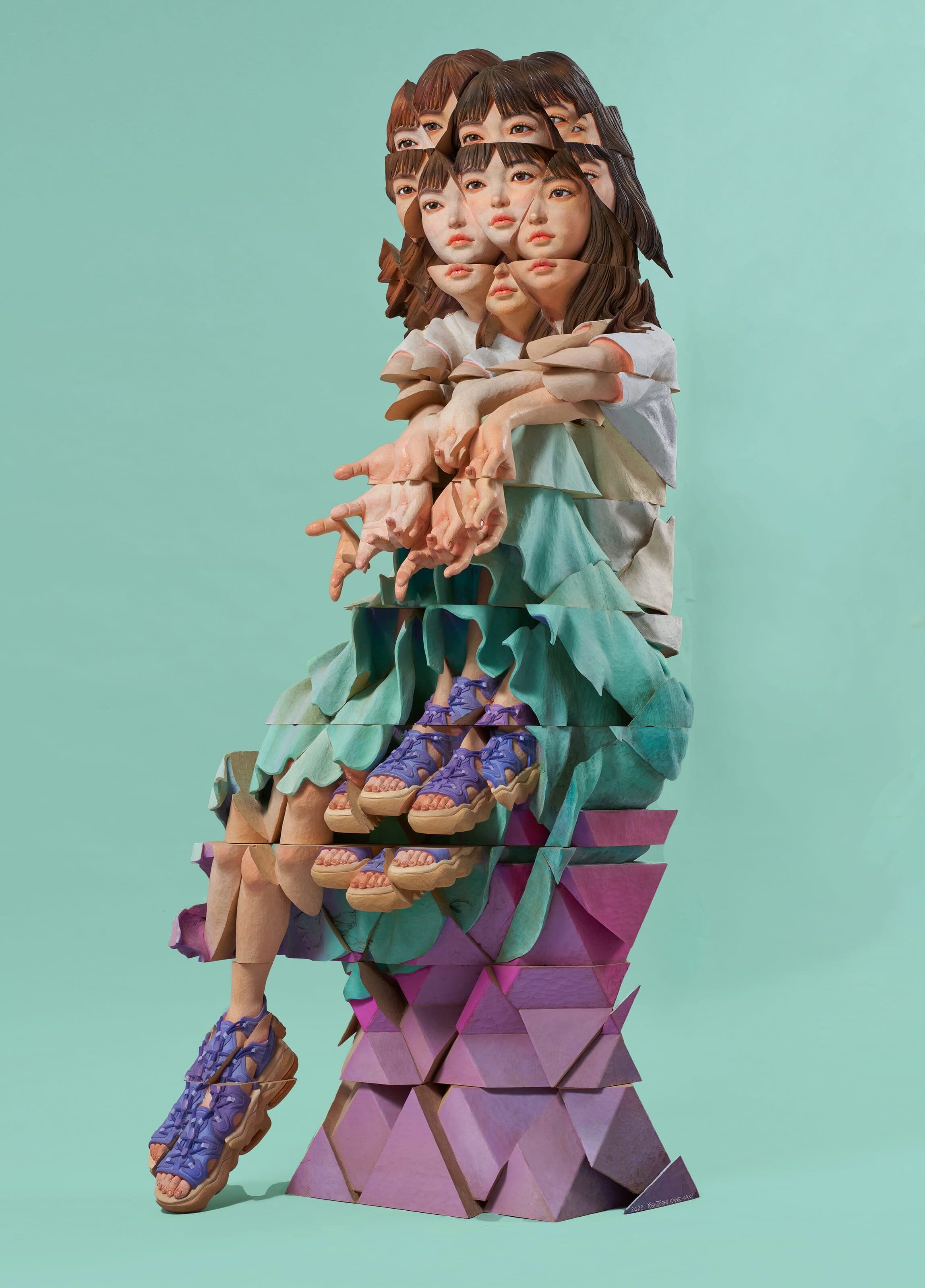 a wooden sculpture by Yoshitoshi Kanemaki of a seated female figure with prismatic or fragmented features