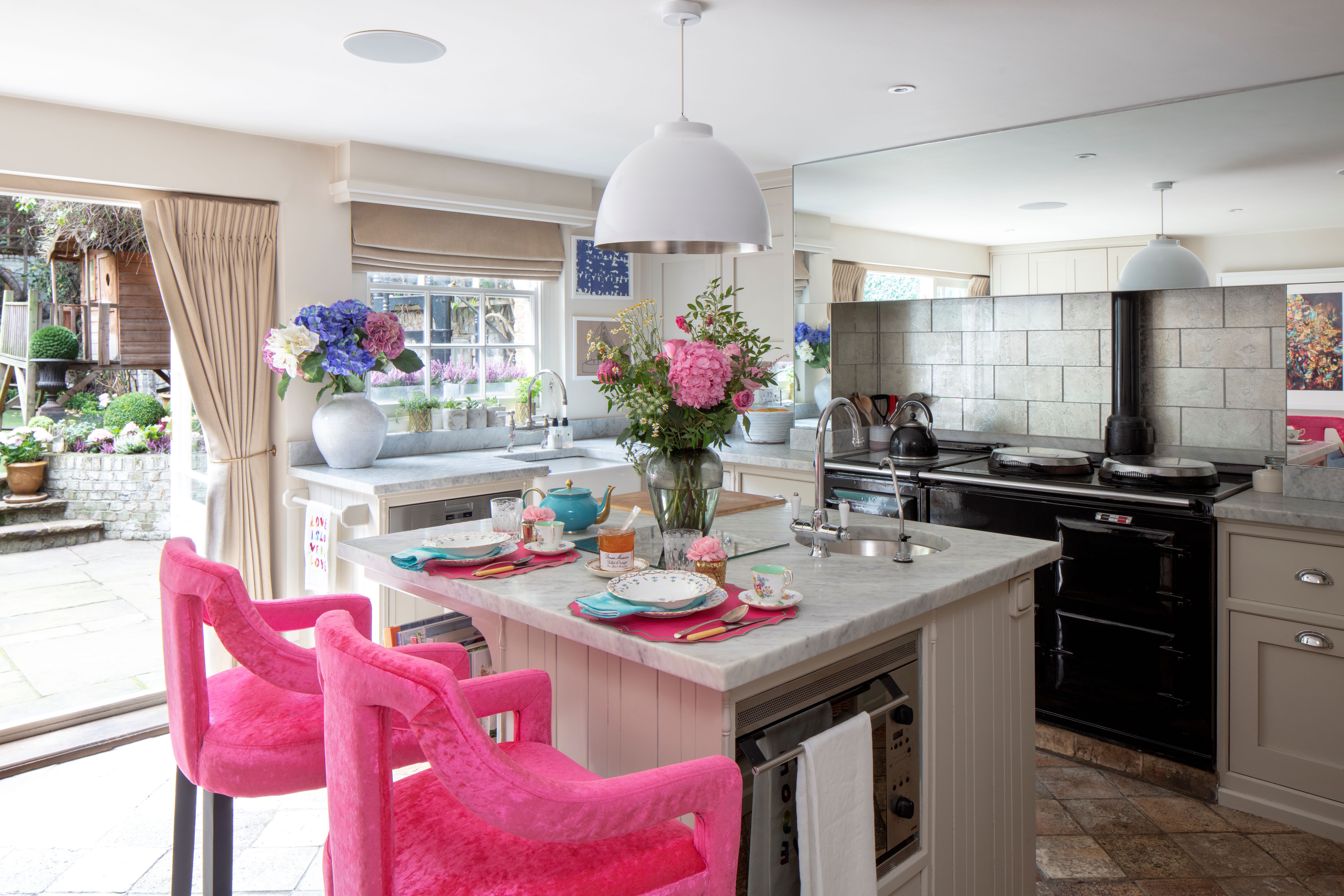 The kitchen of "The Real Housewives of London" star Juliet Mayhew with a set table on a marble counter and pink chairs.