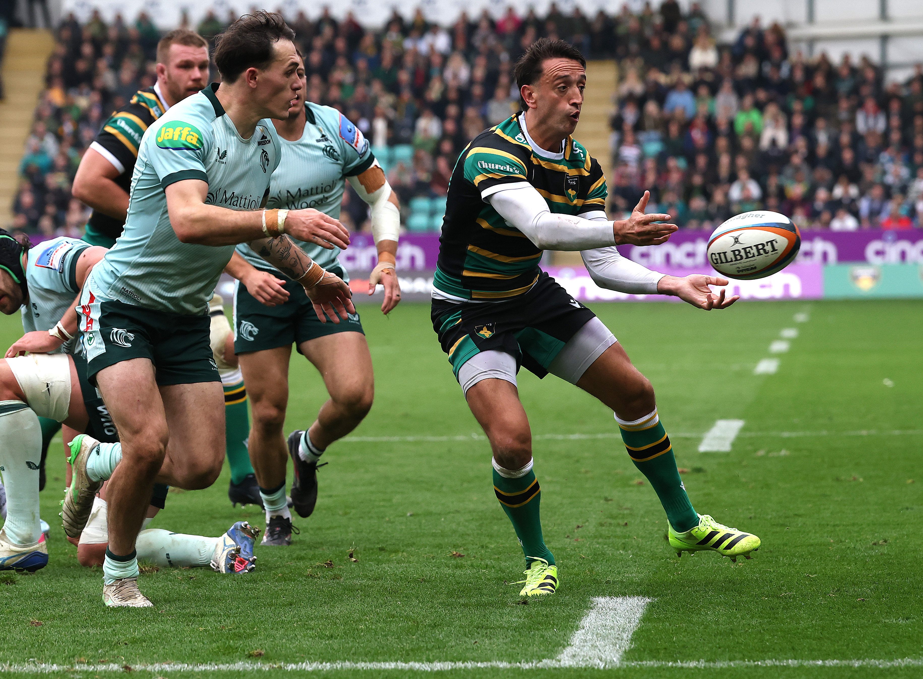 Alex Mitchell of Northampton Saints passes the ball during a rugby match.