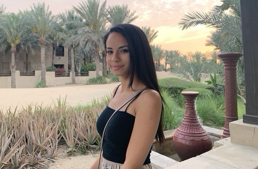 Isabel Sanchez, 28, poses in front of palm trees and desert landscape.