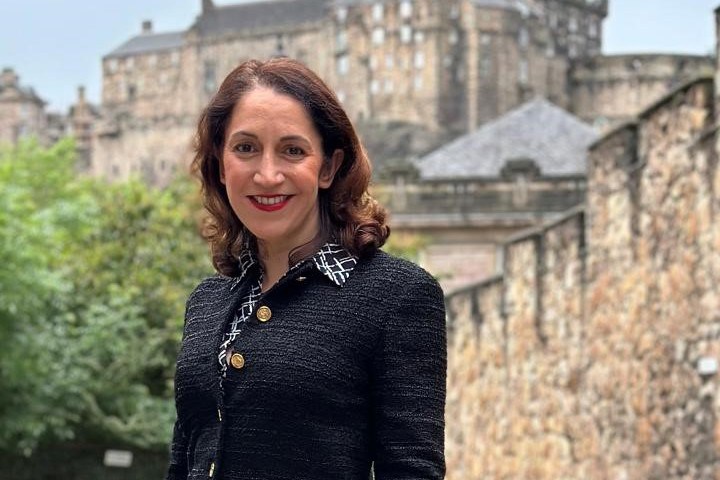 Katerina Brown, Chief Executive of Historic Environment Scotland, smiles with Edinburgh Castle in the background.