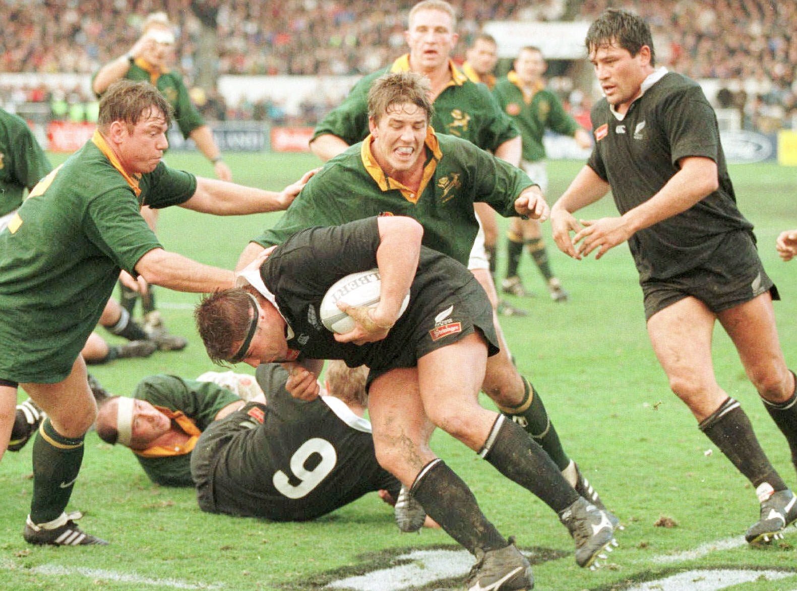 New Zealand's Craig Dowd takes the ball toward South Africa's defense, with teammate Zinzan Brooke looking on.