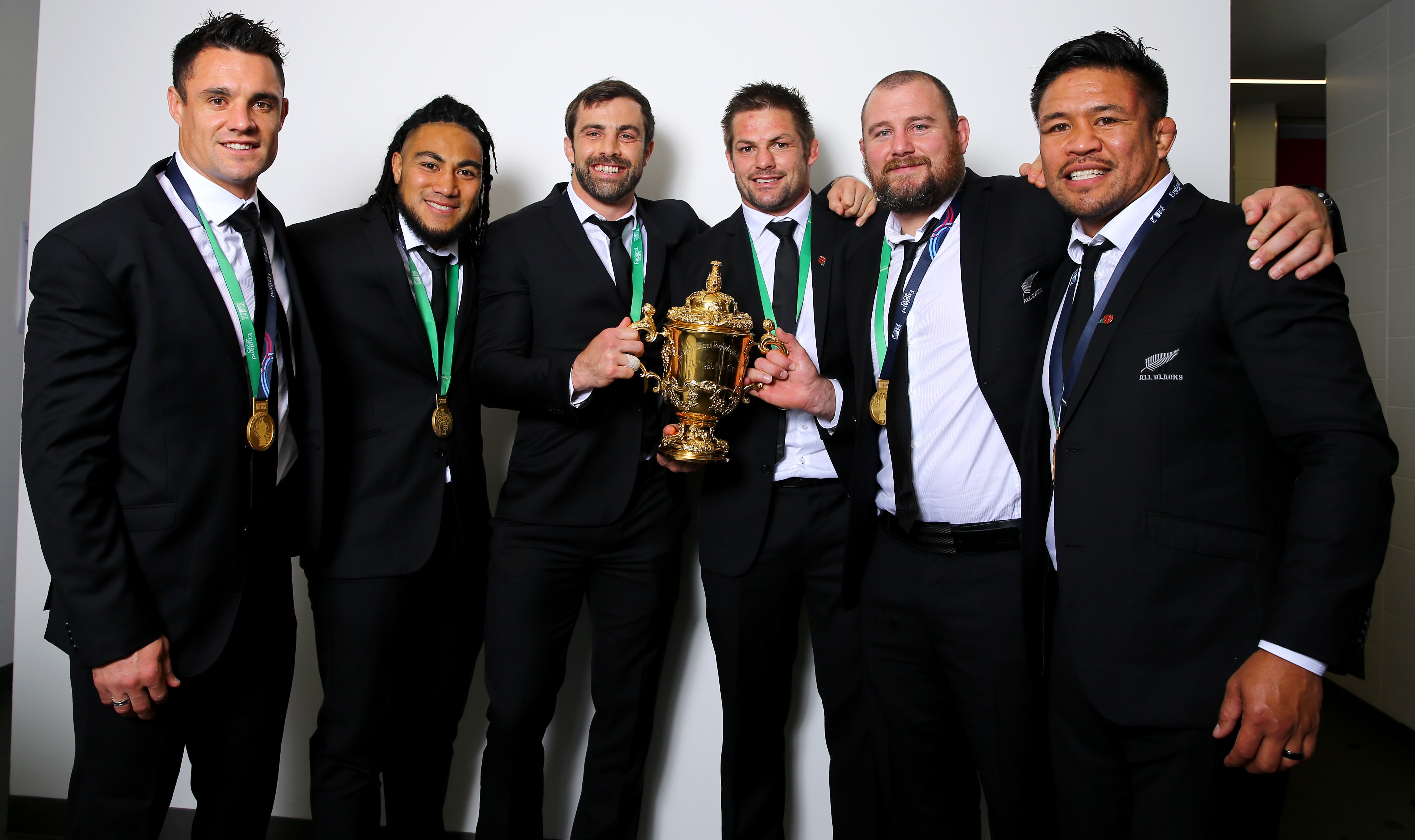 New Zealand All Blacks players Dan Carter, Ma'a Nonu, Conrad Smith, Richie McCaw, Tony Woodcock, and Keven Mealamu posing with the Webb Ellis Cup after winning the 2015 Rugby World Cup.