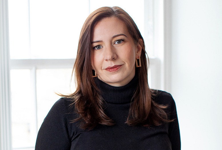 Laura Weldon, 40, from Manchester, wearing a black turtleneck and black leather skirt, standing by a window.