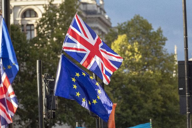 Stock image of a Union flag and EU flag outside the Houses of Parliament, London.