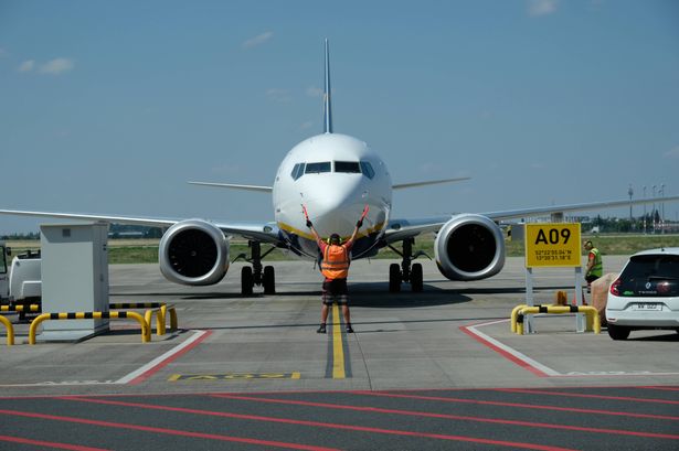 Berlin, Germany - 06 26 2024: Aircraft Marshaller guides Ryanair Airplane to the parking appron at Berlin Brandenburg Airport, Germany.