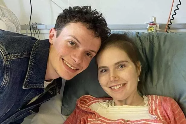 A young woman in a hospital bed with someone by her side
