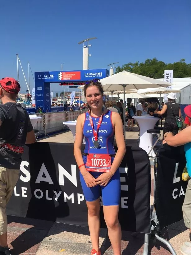 A young woman posing with a medal after a sporting event