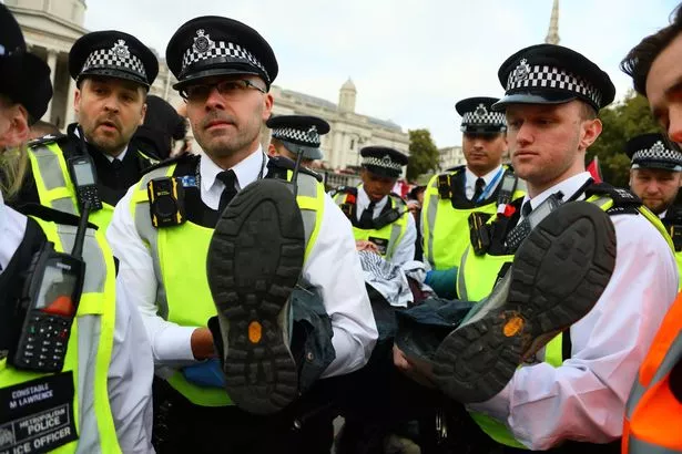 Police officers detain a demonstrator in Trafalgar Square