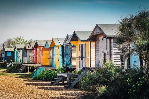On the beach at Whitstable, UK.  Colourful beach cabanas lined up ready for the summer vacation.