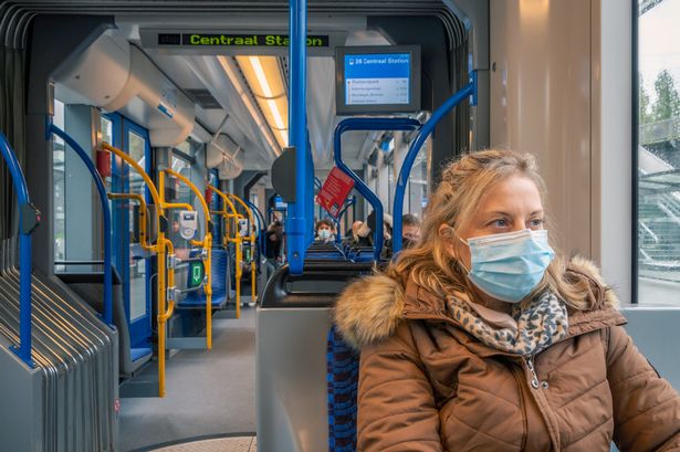 This is a photo of a woman sitting on public transportation wearing a facemask during coronavirus pandemic.