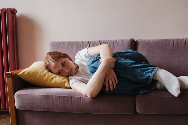 Depression and anxiety in teens. Sad depressed teen girl hugging knees while lying on sofa at home, worrying, upset teenager feeling lonely, thinking about abortion. Melancholy and sadness in women