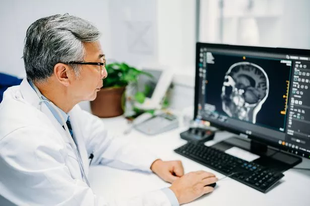 Asian senior male doctor is reading a CT scan at hospital.