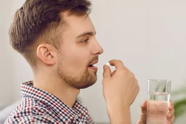 Side view of a man taking medicine. 