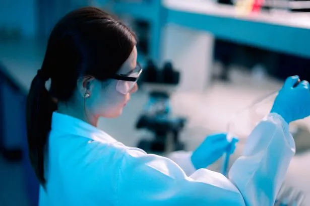 A mature healthcare professional inspects a test tube containing a medical sample. Scientists at the research centre are confident. She is in the lab.