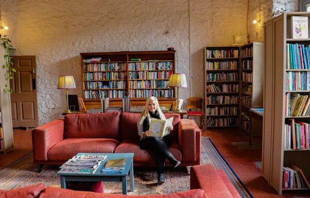 woman sat in room with bookshelves and sofas