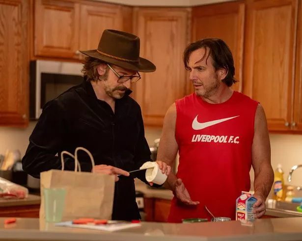 Will Arnett's Alex in a Liverpool vest while talking to Arnie, played by Bradley Cooper, in Is This Thing On?