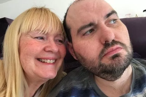 A blonde older woman with a younger man with dark facial hair 