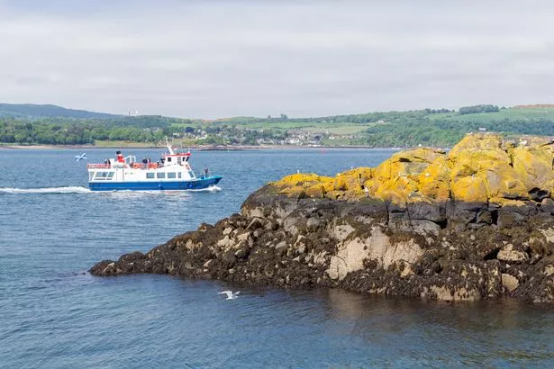 Launch ship appoaching Inchcolm Island with medieval abbey near Scottish Edinburgh