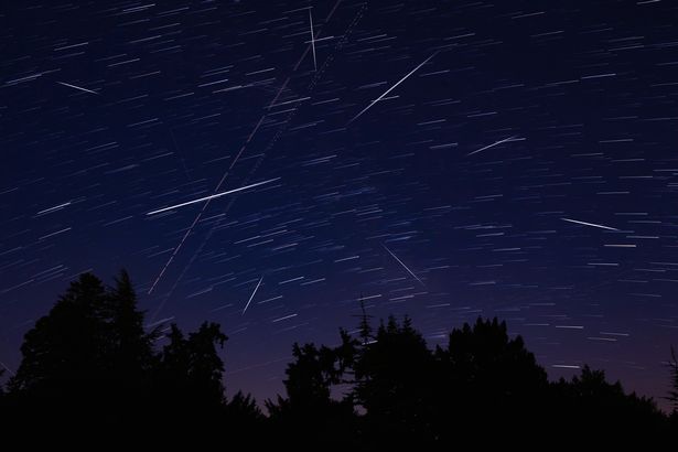 Milky Way stars with meteor shower trails and countryside silhouettes
