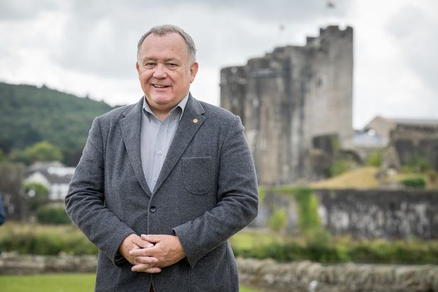 Man in a blazer in front of Caerphilly Castle