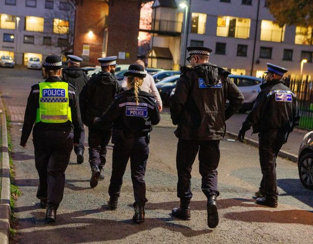 Police patrol walking through Freehold estate in Rochdale