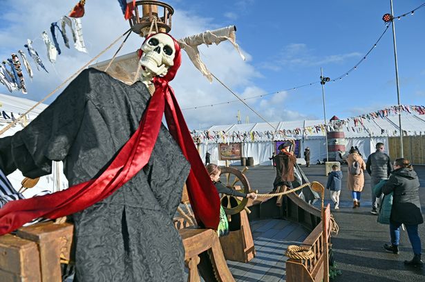A skeleton with a red cloth hanging from it and a marquee and flags in the background