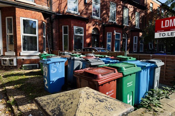Manchester, UK - September 23, 2025: Urban scene with multiple waste bins lined up beside brick homes in Manchester, UK today.