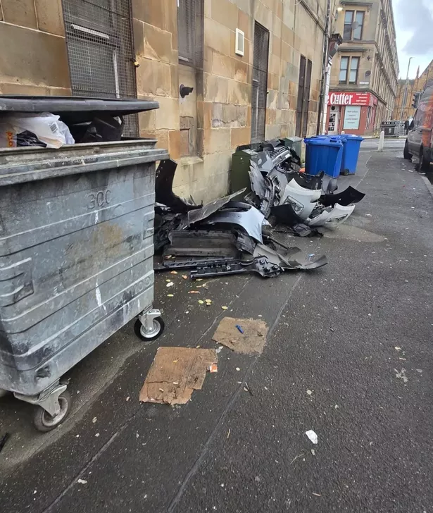 The car parts were dumped next to bins.