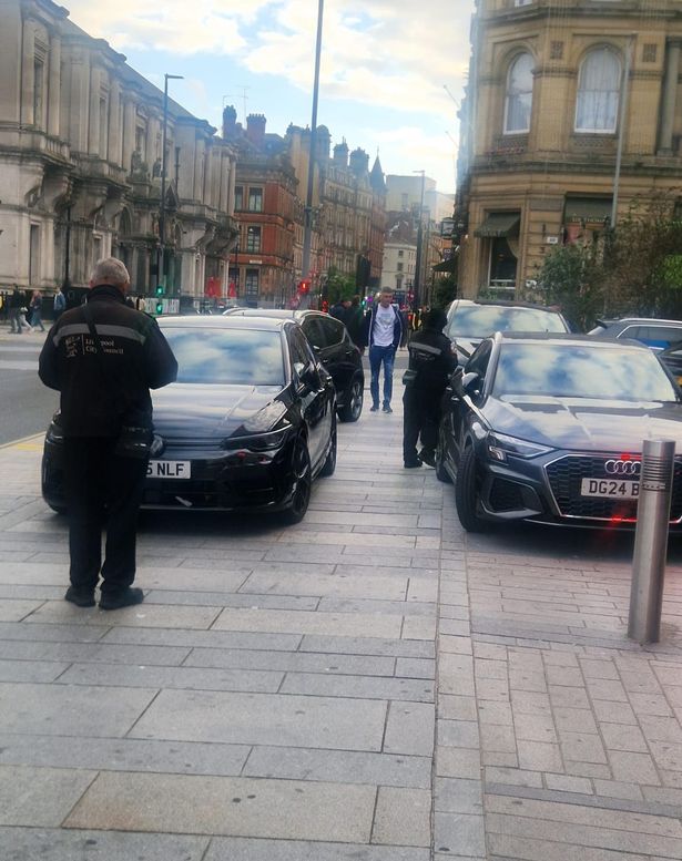 A Liverpool Council parking officer is seen handing out tickets to cars parked on the pavement in Victoria Street