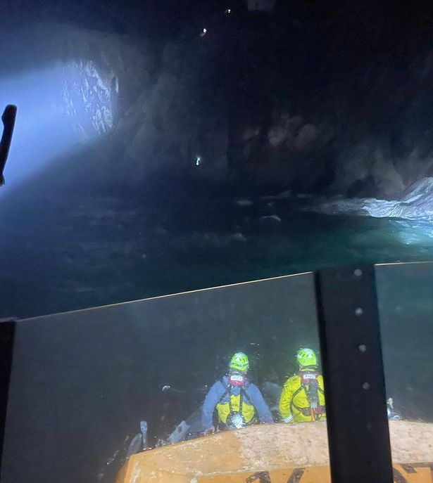 Two RNLI  officers on a boat below cliff
