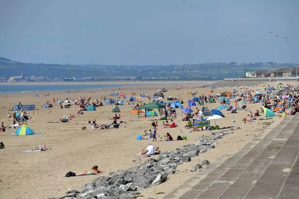 People enjoy the fine, warm, sunny weather by the beach in Aberavon beach, Port Talbot, Wales.
