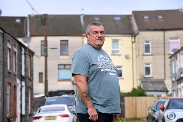 A man standing in a street of terraced houses