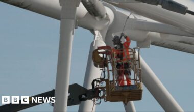 A worker in safety gear operates a lift to clean roof truss structure of London Stadium.