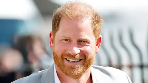 Getty Images Prince Harry in light grey suit smiles at the camera