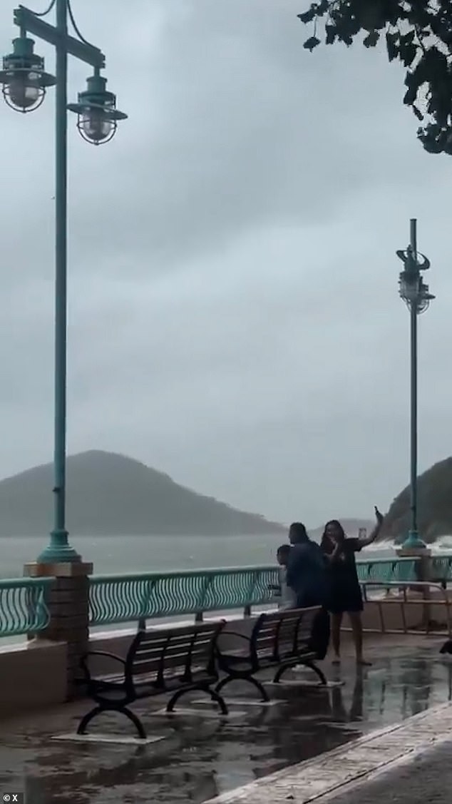 This is the terrifying moment two women and a child were swept aside by powerful sea waves as they posed for photos during Typhoon Ragasa