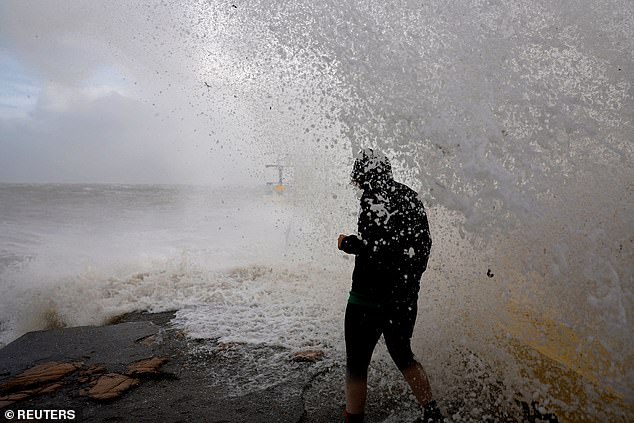 A woman is caught by a large wave at Blackrock diving tower in Galway, Ireland as Storm Amy unleashes over the British isles