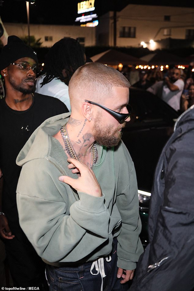 The star was seen with a green hoodie as he hopped out of a vehicle, with his suited bodyguard shielding him from a sea of fans