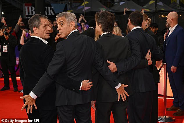 George Clooney showed he hasn't lost his mischievous side as he put on a cheeky display at the star-studded London premiere of his new Netflix film Jay Kelly on Friday evening (L-R David Heyman, George, Noah Baumbach, and Adam Sandler)