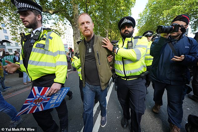 Police officers lead away a demonstrator from Our Fight after the group infiltrated a pro-Palestine march this afternoon