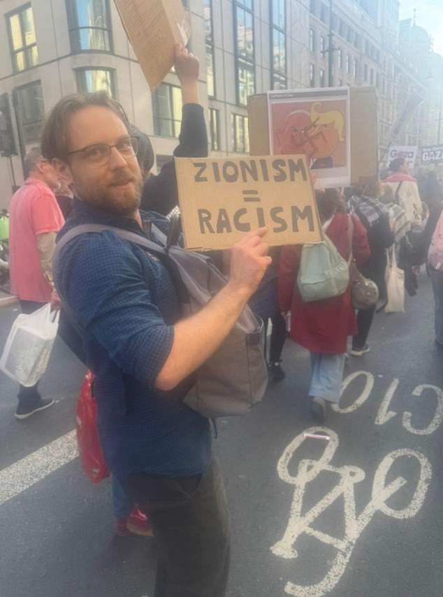 A pro-Palestine protester holds a sign depicting Benjamin Netanyahu and Donald Trump with a swastika