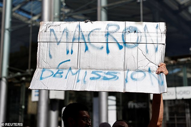 A protester holds a placard which reads "Macron resignation" during a Let's Block Everything protest in France, September 18, 2025