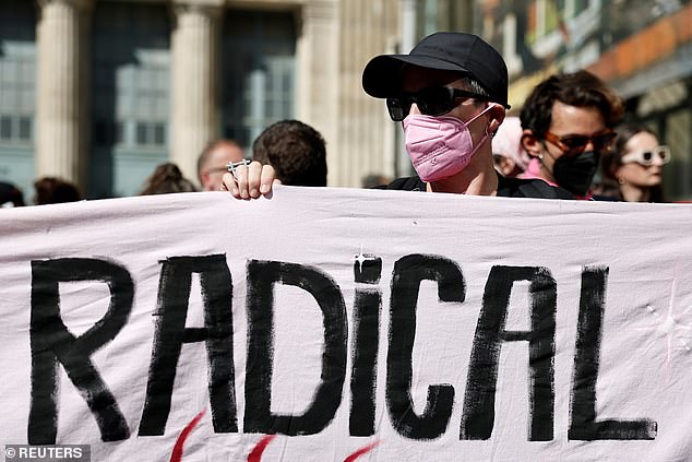 A masked protester holds a banner which reads "Radical" during a Let's Block Everything protest in Paris, France, September 18, 2025