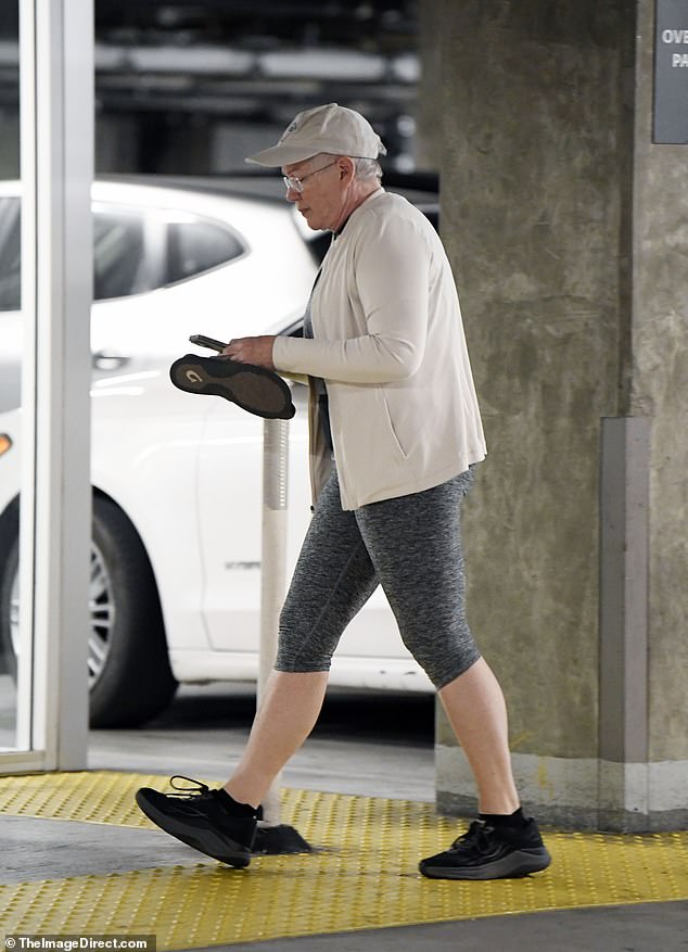 For accessories, she wore black sneakers, prescription glasses and a white baseball cap while carrying a pair of comfortable flip-flops