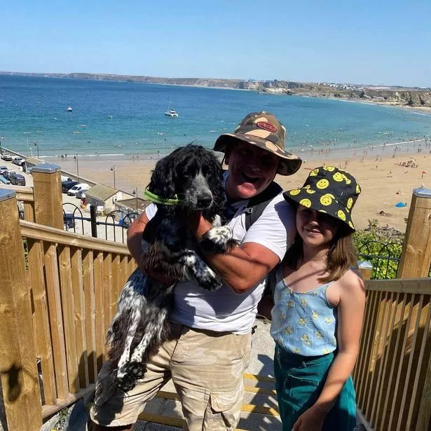 Jason holding a black dog in his arms, standing next to his daughter who is hugging me