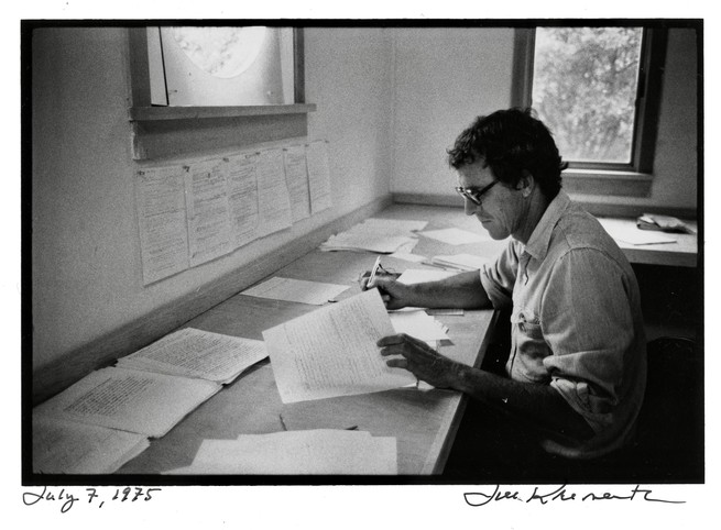 A black and white photograph of Matthiessen at his writing desk