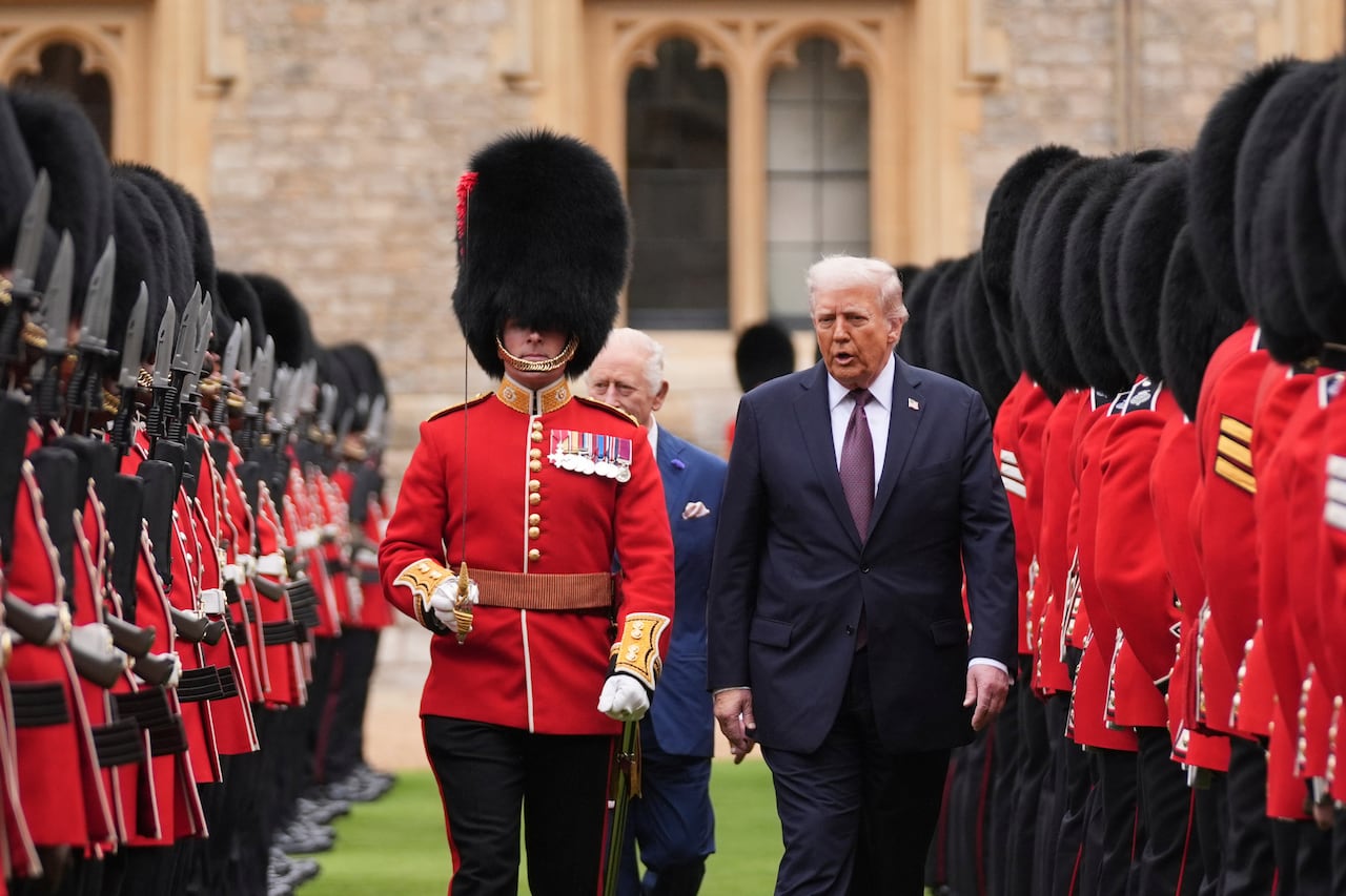 A guard of honour escorting a man as he inspects a guard of honour with another man behind them on the grounds of a castle.