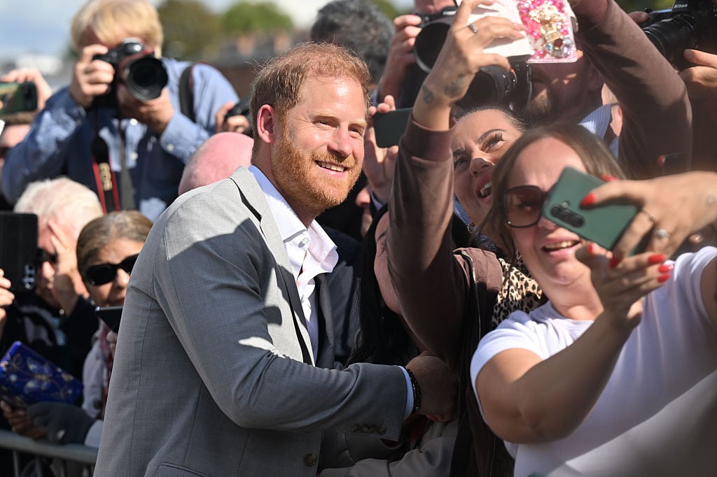 A person leans toward several people taking selfies with them in it.