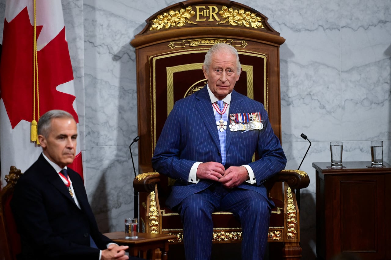 A man sits on a throne with another man sitting to his right.