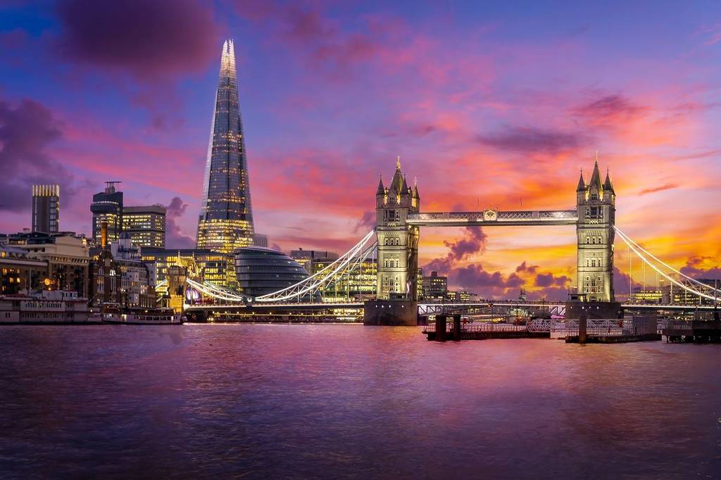 London skyline featuring The Shard, Tower Bridge and River Thames at dusk under a pink and purple sky